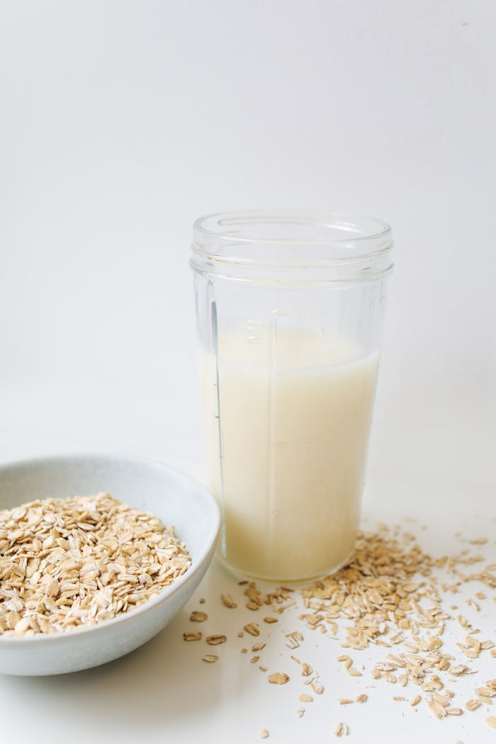 Close-up of a glass of oat milk with a bowl of oats, vegan and healthy lifestyle concept.